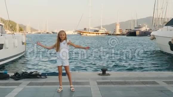 开朗的少女在码头上跳舞在海港和游艇背景快乐的女孩在河堤船上和视频的预览图