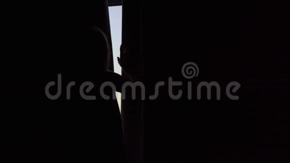 一位年轻女子在一间公寓里可以看到海岸和日出的全景她打开窗帘视频的预览图