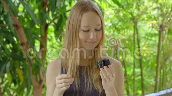 一个绿色环境中的年轻女性用黑色活性炭粉刷牙用于牙齿美白她用的是视频的预览图