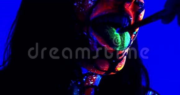 接近一个女人她的舌头上有发光的油漆紫外线4k视频的预览图