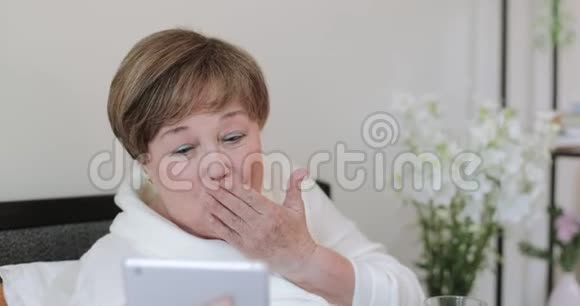 快乐成熟的女士挥手购买和吹吻同时完成视频通话平板电脑在家抢劫录像的老妇人视频的预览图