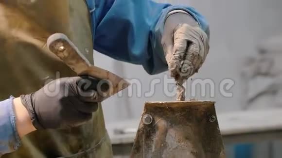 混凝土车间一名男子用铲子涂抹形状的混凝土遗骸视频的预览图