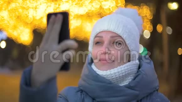 一位女游客在冬季公园里对着花环与家人通过视频通话视频的预览图
