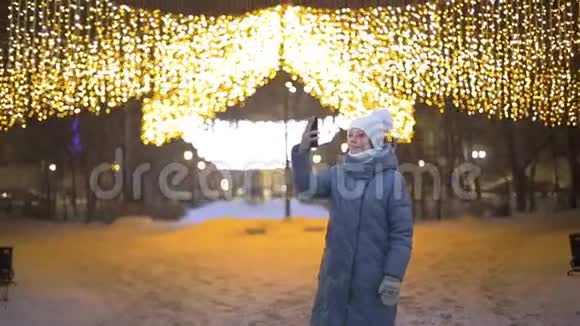 一位女游客在冬季公园里对着花环与家人通过视频通话视频的预览图