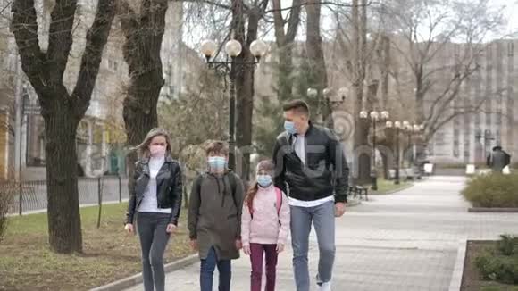 一家人戴着口罩在公园散步以防流感病毒或冠状病毒视频的预览图
