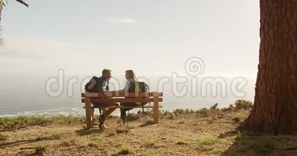 活跃的老夫妇坐在森林的长凳上视频的预览图