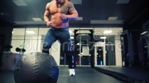 一个成年男性健美运动员举起一个沉重的球把它放回地板上视频的预览图
