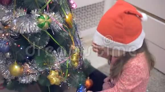 圣诞树附近的小女孩在考虑圣诞玩具视频的预览图
