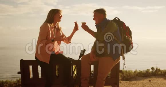 活跃的老夫妇在森林里坐在长凳上吃饭视频的预览图