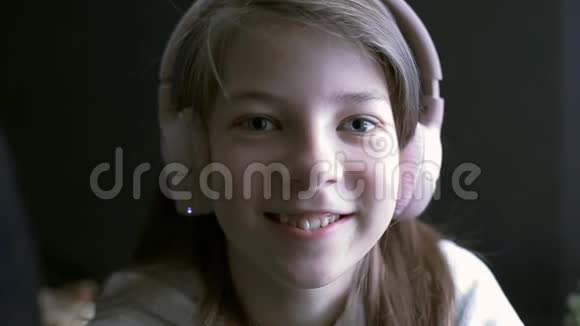 一个十几岁的女孩用耳机听音乐视频的预览图