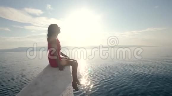 一个年轻的女人坐在船的边缘美丽的阳光视频的预览图