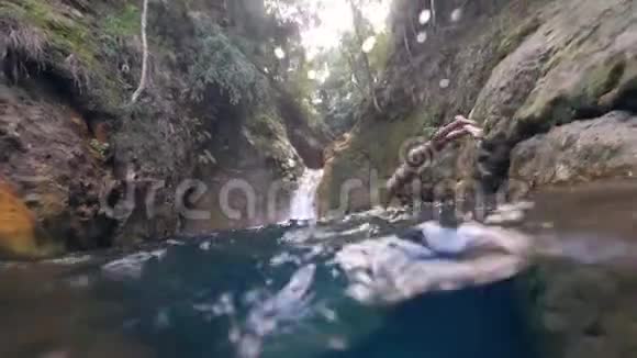 一位年轻女子在瀑布处潜入水中视频的预览图