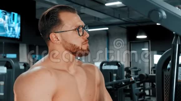 一个戴眼镜的胡子男健美运动员在健身房做力量锻炼视频的预览图