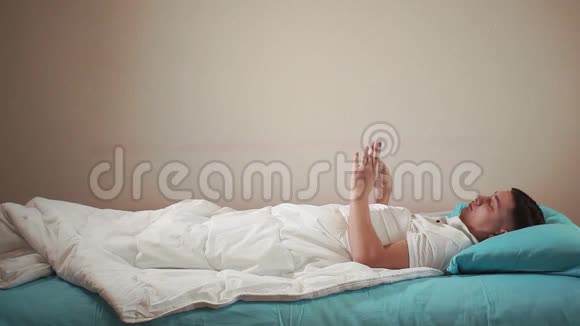 上床睡觉一个年轻人在他的手机上设置闹钟准备睡觉视频的预览图