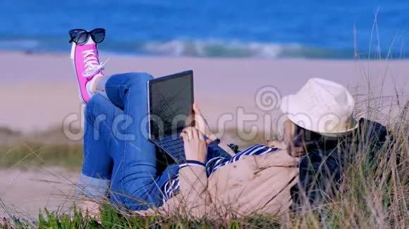 自由职业概念女人在海滩上的笔记本上工作视频的预览图