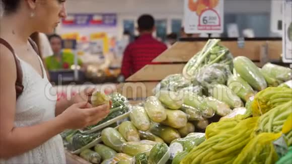 年轻女子在超市购物健康食品玉米在市场超市选择食物视频的预览图
