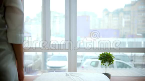 按摩美丽而年轻的按摩师坐在一个有大窗户的柜子里的沙发附近视频的预览图