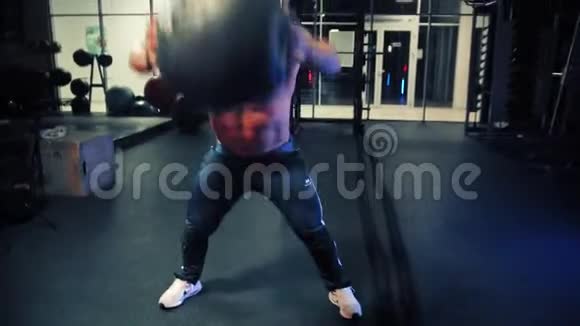 一个成年男性健美运动员跑起来举起一个沉重的球并把它放回地板上视频的预览图