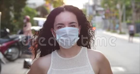 一个戴着冠状病毒流行的面具的年轻女人的肖像是在街上戴着保护性询问健康概念视频的预览图