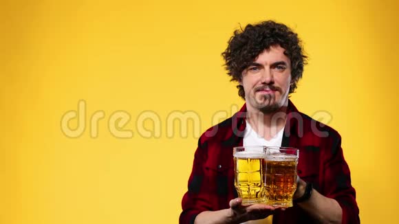 圣帕特里克节年轻的啤酒节男子提供大啤酒杯与饮料隔离在黄色背景他还好视频的预览图