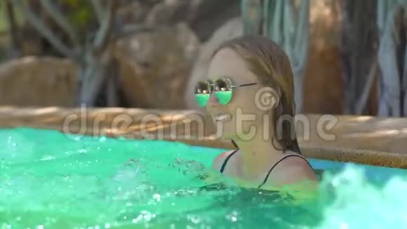 一位年轻女子在热带度假胜地有温泉瀑布和游泳池有热水视频的预览图