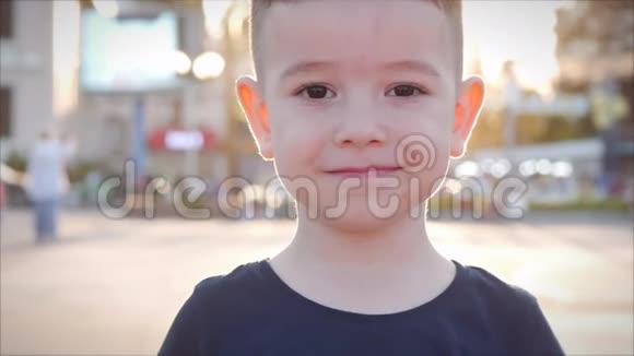 在一个阳光明媚的夏日滑稽的小男孩微笑着看着街上的摄像机快乐的脸上有一个学龄前儿童视频的预览图