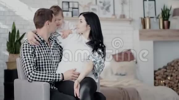 一位美丽的孕妇她英俊的丈夫和他们的小儿子正在聊天微笑着亲吻消费视频的预览图