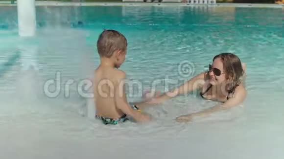 妈妈和她的小儿子在游泳池里玩视频的预览图