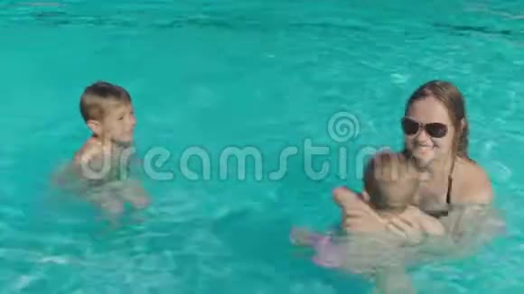 年轻的妈妈在游泳池里玩孩子视频的预览图