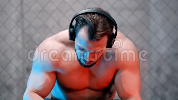 一个戴着耳机坐在长凳上喝瓶子里的水的有魅力的拳击手视频的预览图