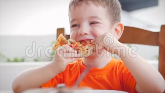 可爱健康的学龄前小男孩坐在儿童咖啡馆里吃意大利披萨快乐的孩子急切地吃视频的预览图