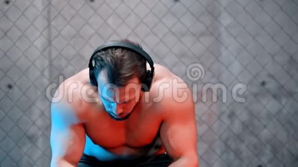 坐在长凳上戴着耳机的漂亮拳击手视频的预览图