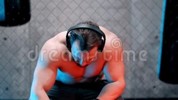 一个戴着耳机坐在长凳上喝水的漂亮拳击手视频的预览图