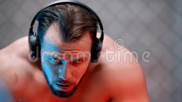 戴着耳机坐在长凳上的疲惫的拳击手视频的预览图