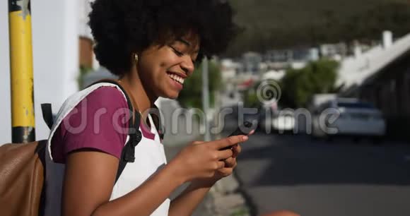 人行道上智能手机上的混血女人视频的预览图