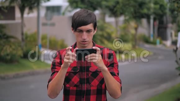 年轻人拿着智能手机在城市街头户外玩手机游戏快乐的年轻人使用社交媒体应用程序工作学习视频的预览图