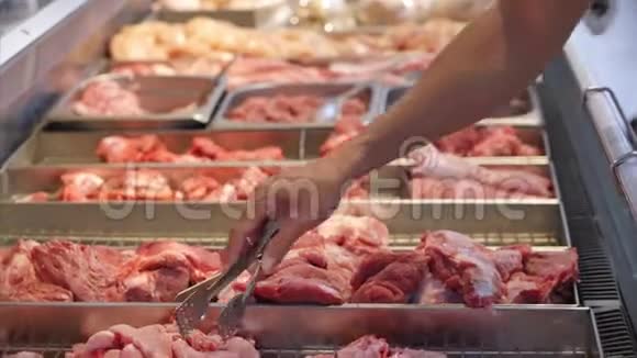 购买者的手在商店里男性的手特写选择或购买肉片用钳子在市场上在市场上视频的预览图