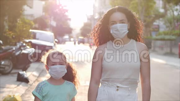 妈妈和女儿正站在一条街上戴着防护面具以防止covidn1h1流行健康和安全概念视频的预览图