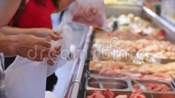 肉类部门的超市里的买家正在挑选袋子里的肉来称重和购买人们买肉视频的预览图