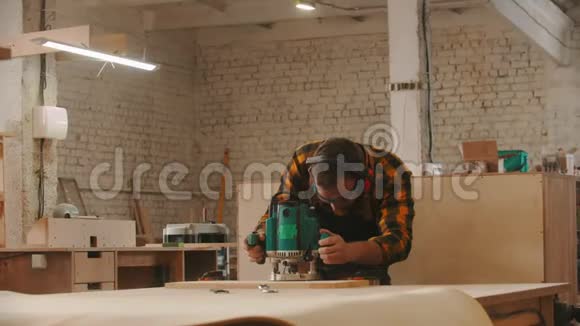木工行业工人戴防护眼镜和耳机在车间打磨木制物品视频的预览图