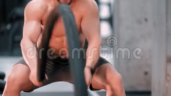 一位年轻有魅力的健美运动员在体育馆里奋力与绳索搏斗视频的预览图