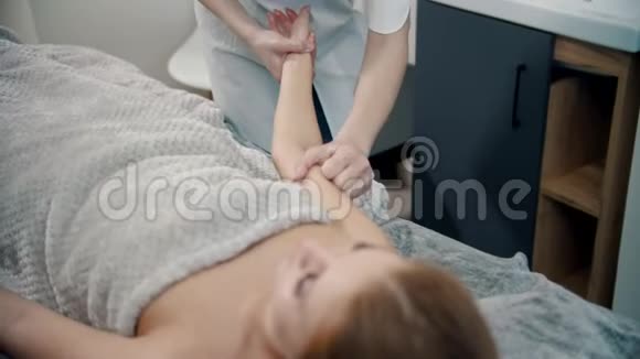 按摩女性按摩治疗师按摩躺在沙发上的女人的手用特殊的按摩技术视频的预览图
