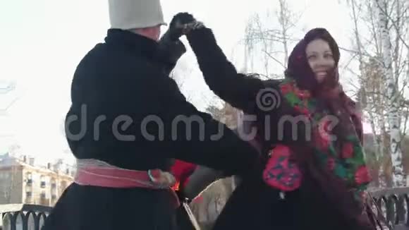 穿着俄罗斯传统服装的俄罗斯男女在冬天的桥上跳舞视频的预览图