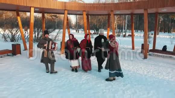 俄罗斯民俗穿着服装的俄罗斯人正在雪地公园跳舞视频的预览图