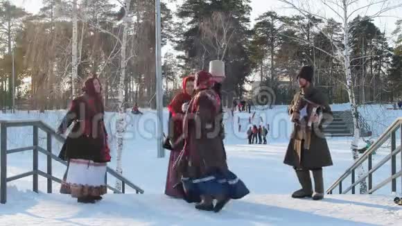 穿着俄罗斯民族服装的俄罗斯男女在阳光明媚的天气里跳着传统舞蹈视频的预览图
