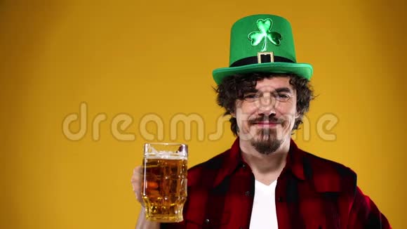 圣帕特里克节年轻的啤酒节男子提供大啤酒杯与饮料隔离在黄色背景动作缓慢视频的预览图