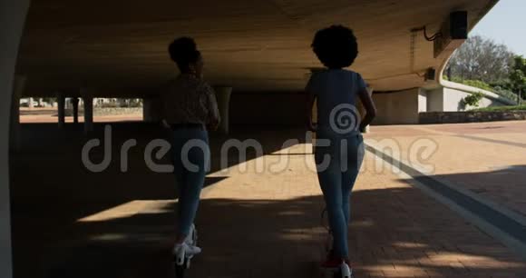 桥下两个骑电动滑板车的混血女视频的预览图