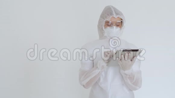 一个化学防护的女孩在电子平板上打印数据然后看着相机一个穿白色一次性衣服的女孩视频的预览图