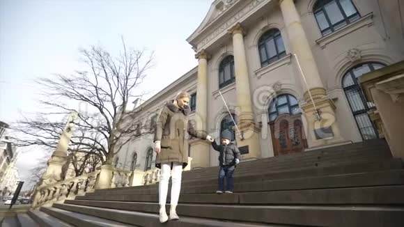 年轻的母亲帮助儿子走下国家美术馆的楼梯慢动作视频的预览图