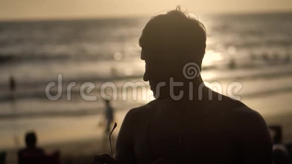 日落时海滩上肌肉男的剪影视频的预览图